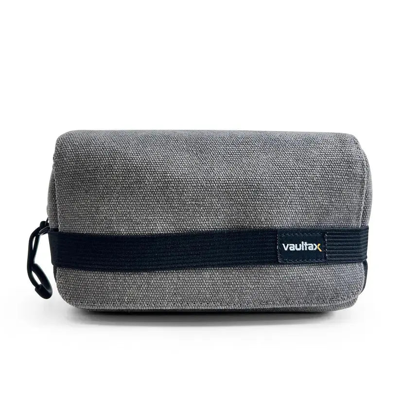 A gray textured canvas pouch with a black elastic band and a small 'Vaultlax' logo patch, shown on a clean white background.