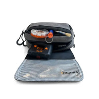 A gray Vaultlax zippered travel pouch shown open on a white background, with a black Mighty Plus Medic device and small vaporizer accessories placed inside. The pouch is laid over a silver mesh travel pad, and the brand name 'Vaultax' is visible on the pouch.